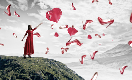 Beautiful woman in red dress reaching hand in gestureの写真素材