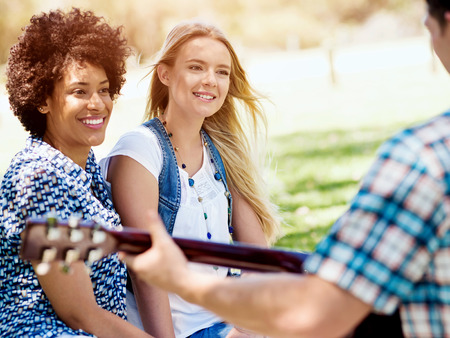 Group of young friends with guitar having fun outdoor