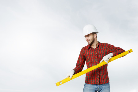 Young handsome man in hardhat with measure levelの写真素材