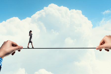 Businesswoman with blindfolder on eyes balancing on the ropeの写真素材