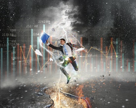 Determined businessman jumping over crack in asphalt roadの写真素材