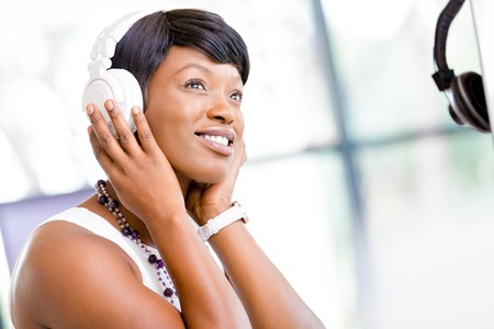 Young beautiful businesswoman listening music in headphones at officeの写真素材