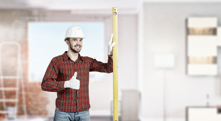 Young handsome man in hardhat with measure level. Mixed mediaの写真素材