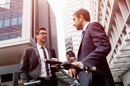 Young businessman with bike talking to his colleagueの写真素材