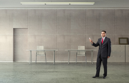 Elder businessman using his mobile phone at modern dark office interior. Mixed mediaの写真素材