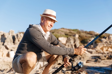 Senior man fishing with rod at seasideの写真素材