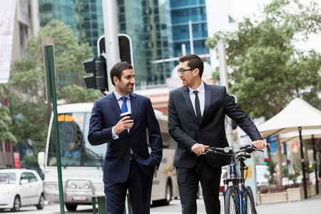 Young businessman with bike talking to his colleagueの写真素材