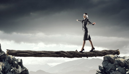 Blind businesswoman walking on wooden log above gap. Risk and challenge conceptの写真素材