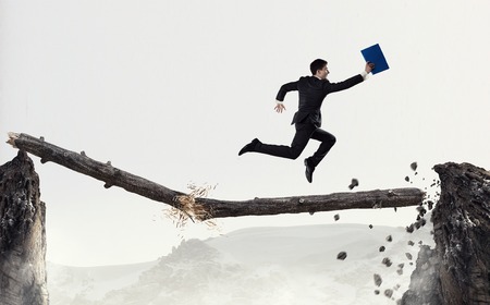 Young successful businessman jumping over gap. Risk and challenge conceptの写真素材