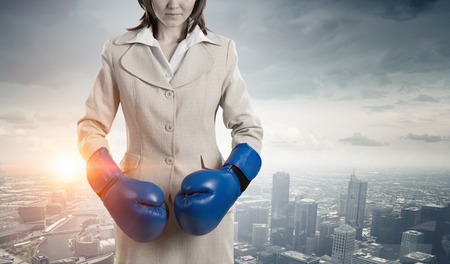 Businesswoman in boxing gloves against city backgroundの写真素材