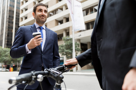Young businessman with bike talking to his colleagueの写真素材