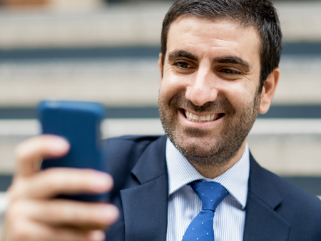 Portrait of young handsome businessman outdoor holding mobile phoneの写真素材