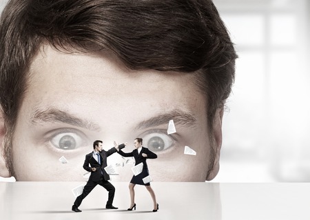 Businessman peeping from under table at people fighting with each other. Mixed mediaの写真素材