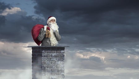 Santa Claus inside brick chimney with his bag of toysの写真素材