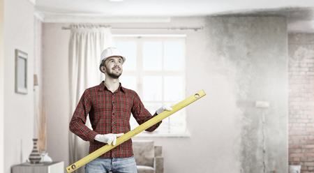 Young handsome man in hardhat with measure level. Mixed mediaの写真素材