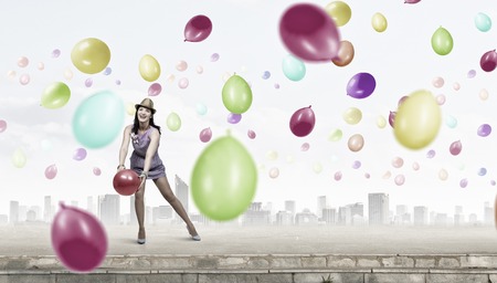 Young woman in dress and hat with party balloonsの写真素材