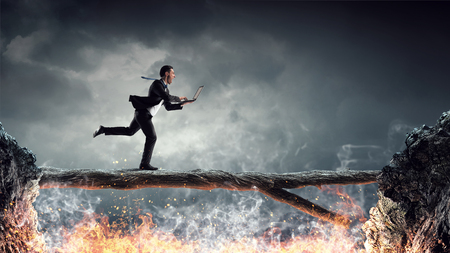 Young successful businessman jumping over gap. Risk and challenge conceptの写真素材