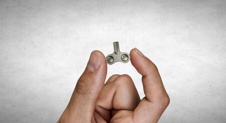 Close of male hand holding key between fingers