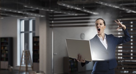 Young elegant businesswoman in office doing magic with laptop. Mixed mediaの写真素材