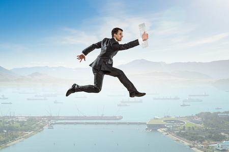 Active businessman jumping high in sky against natural backgroundの写真素材