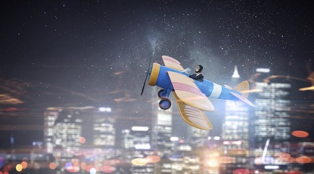 Woman pilot in helmet flying old styled airplaneの写真素材