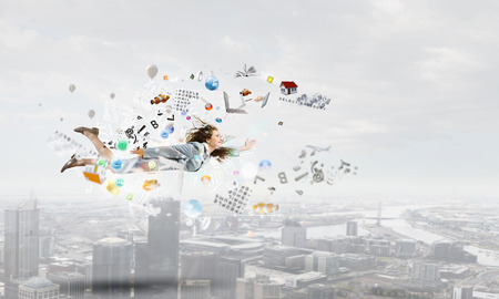 Young cheerful businesswoman flying high in skyの写真素材