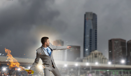 Young aggressive businessman throw burning molotov cocktailの写真素材