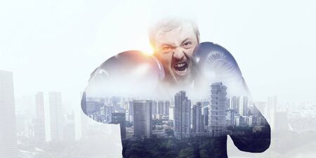 Businessman in boxing gloves against cityscape backgroundの写真素材