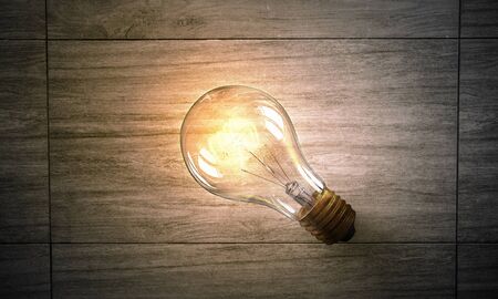 Glass glowing light bulb on wooden backgroundの写真素材