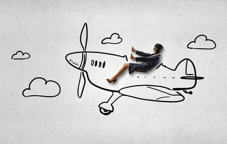 Woman in suit and helmet flying in drawn old styled airplaneの写真素材