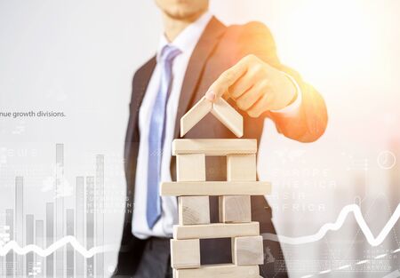 Young businessman building tower of wooden blocks
