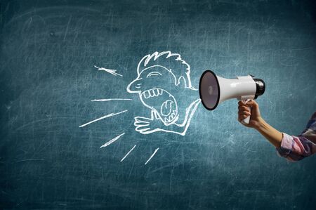 Hand of businessman holding megaphone against chalkboard backgroundの写真素材