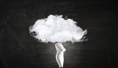 Businesswoman standing with her head in cloudの写真素材
