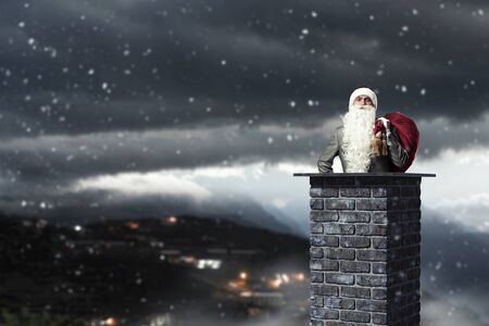 Santa Claus inside brick chimney with his bag of toysの写真素材
