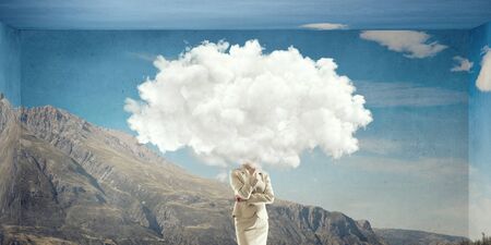 Businesswoman standing with her head in cloudの写真素材