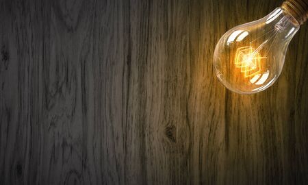 Glass glowing light bulb on wooden backgroundの写真素材