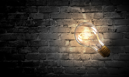 Glass glowing light bulb on brick background