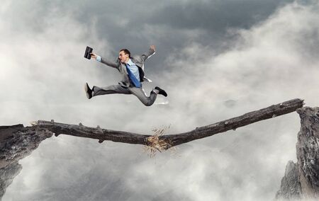 Young successful businessman jumping over gap. Risk and challenge concept