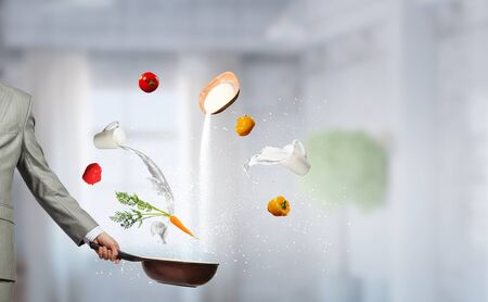 Handsome businessman in cook hat with pan in hands. Mixed mediaの写真素材