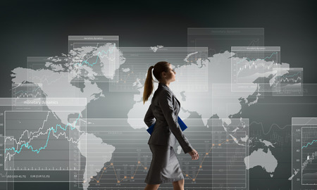 Young businesswoman walking with suitcase against digital backgroundの写真素材