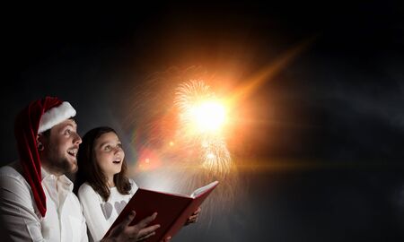 Happy young family of father and daughter reading book together