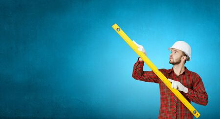 Young handsome man in hardhat with measure levelの写真素材