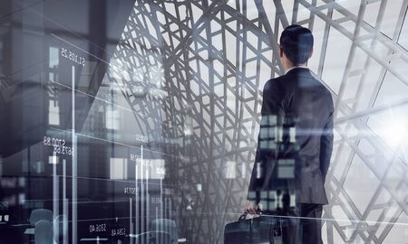 Back view of elegant businessman in suit with briefcase in interior. Mixed mediaの写真素材