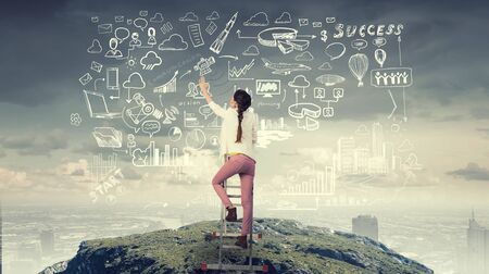 Young pretty woman drawing with chalk her vision of success achievingの写真素材