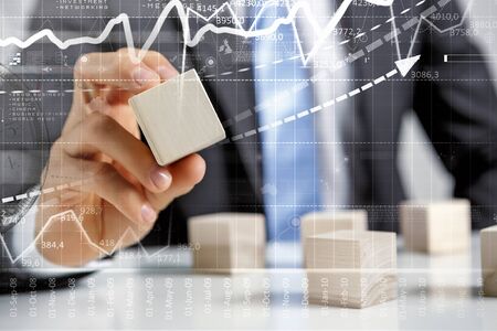 Young businessman building tower of wooden blocksの写真素材