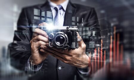 Businessman taking photo with vintage camera . Mixed mediaの写真素材