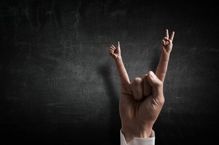 Rock gesture on concrete background . Mixed mediaの写真素材