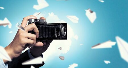 Businessman taking photo with vintage camera . Mixed mediaの写真素材