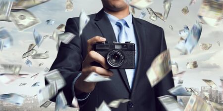 Businessman taking photo with vintage camera . Mixed mediaの写真素材