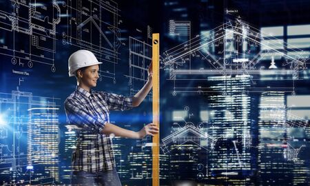 Builder woman taking measures . Mixed mediaの写真素材